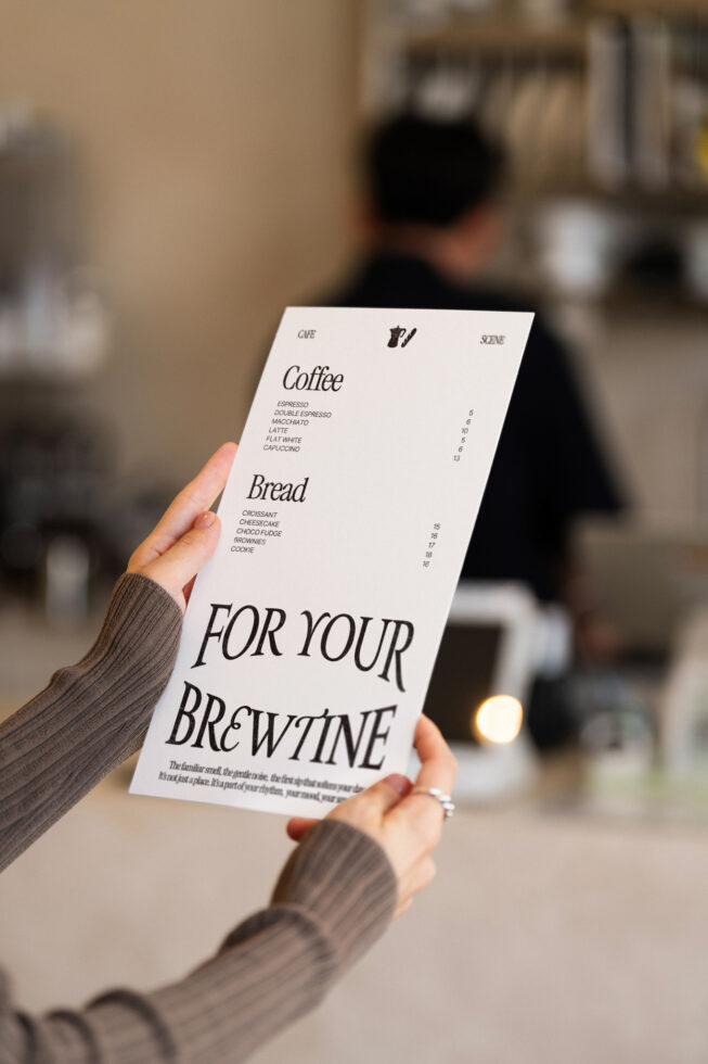 Woman holding single-page menu card with coffee shop offerings in hand
