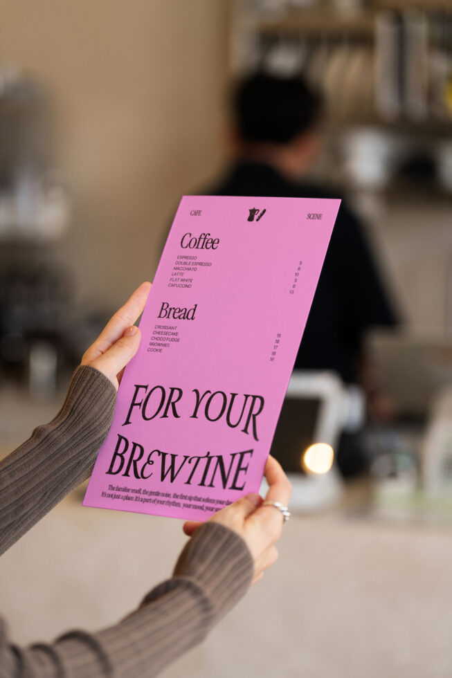 Woman holding bright pink single-page menu with coffee shop details