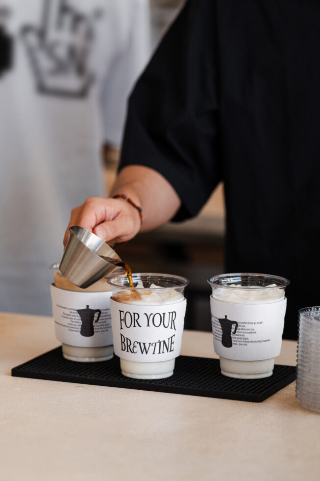 Person pouring espresso into paper cup labeled For Your Brewtine, styled tasting setup