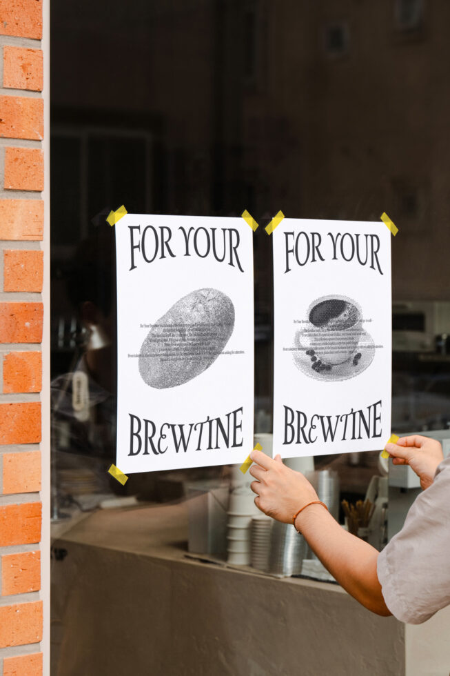 Two posters taped to window with yellow tape showing coffee imagery for brewtine cafe