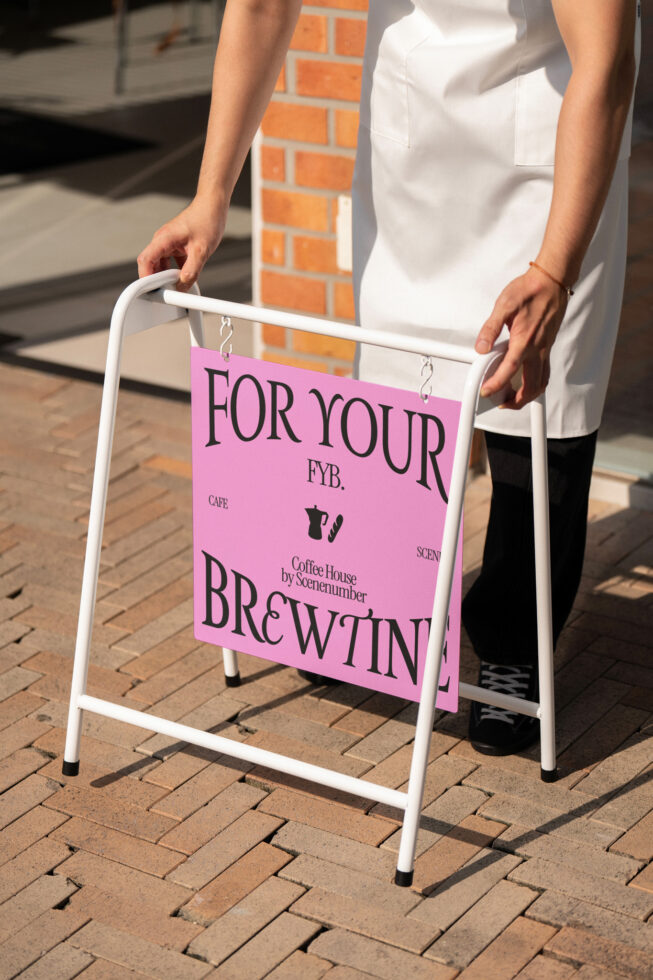 Close-up of hands adjusting white A-frame sandwich board with pink sign panel on sidewalk