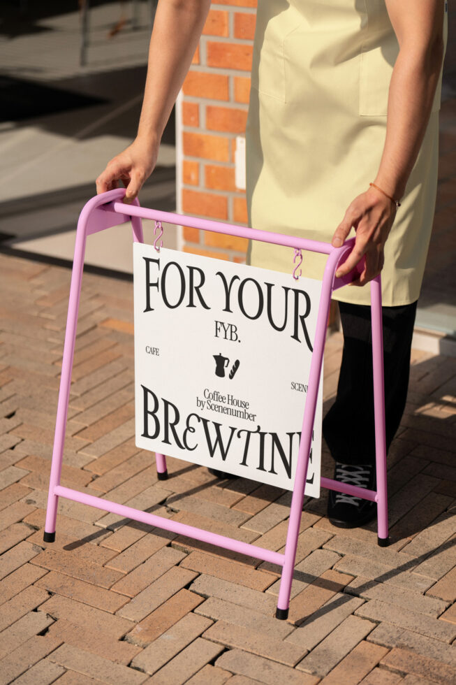 Pink sandwich board A-frame sign held outdoors on brick pathway