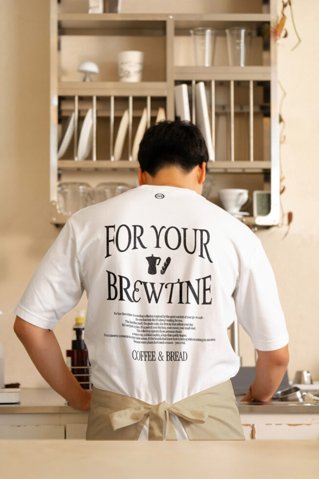 White t-shirt with For Your Brewtine back print worn in minimalist cafe kitchen