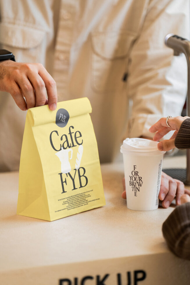 Bright yellow paper bag displaying coffee shop design with takeout cup nearby