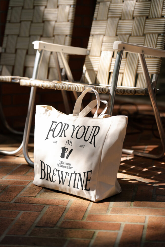 Beige canvas tote hanging on woven chair in outdoor cafe setting