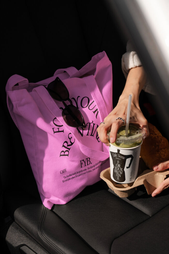 Pink tote bag mockup holding beverage cup for editable brand design