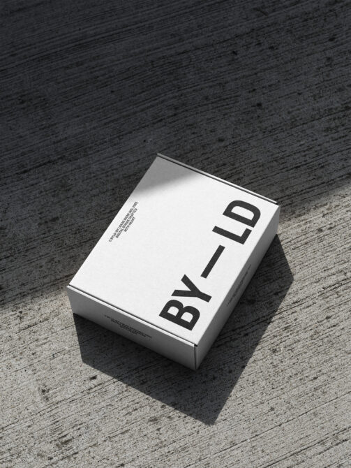Minimalist white packaging box displaying bold black serif typography on pavement