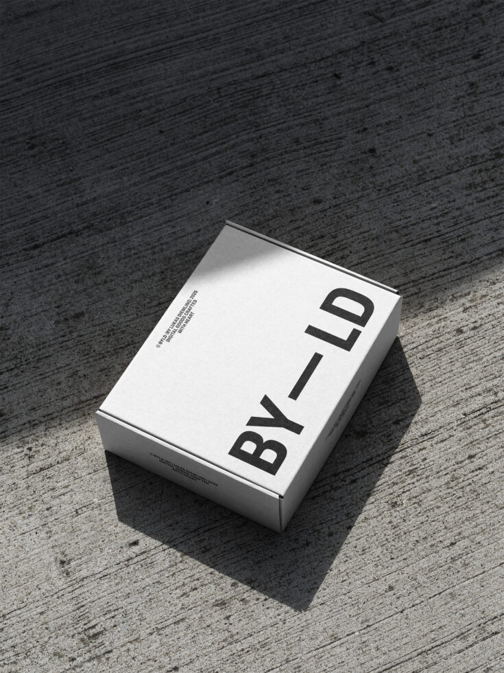 Minimalist white packaging box displaying bold black serif typography on pavement