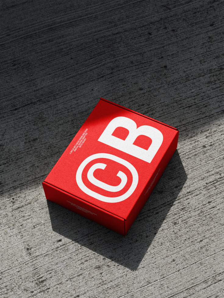 Bright red product box with white geometric logo on concrete surface
