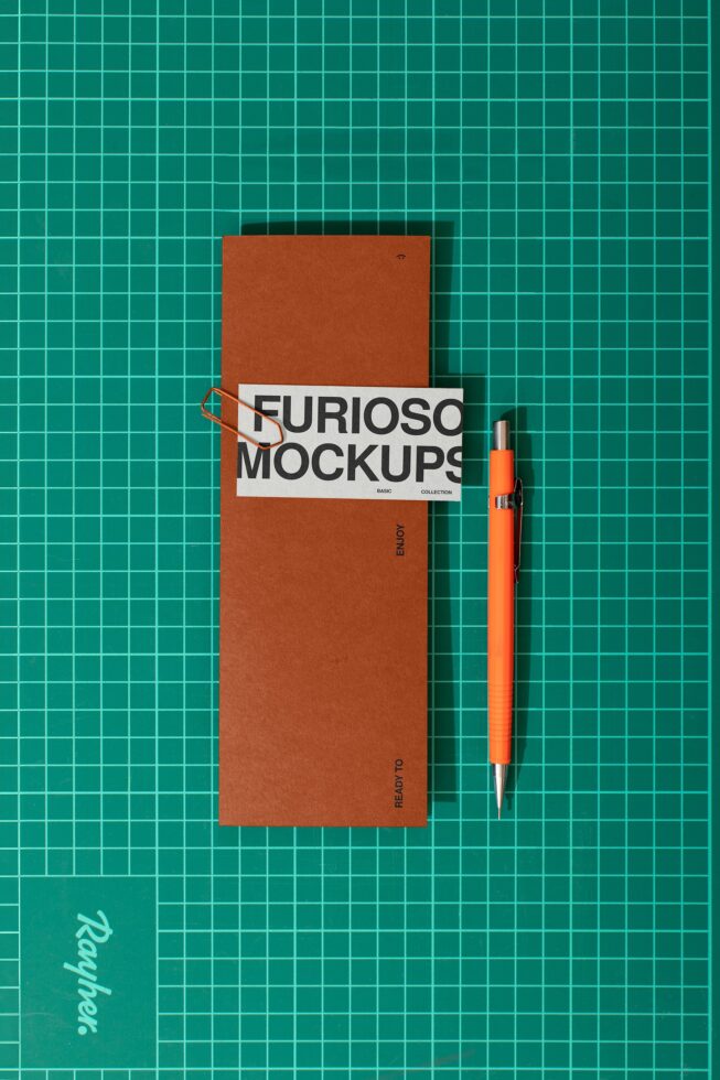 Rust folder with white label band, orange pen on teal gridded background
