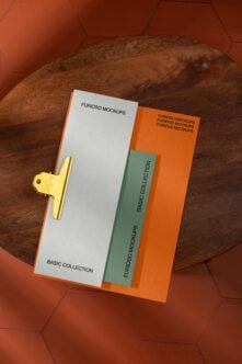 Gold clipboard with stacked branded materials on textured leather surface with orange hexagon backdrop
