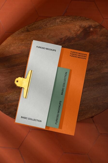 Gold clipboard with stacked branded materials on textured leather surface with orange hexagon backdrop
