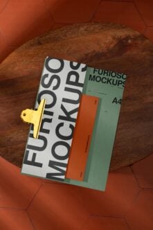 Layered print collateral with bold typography next to green folder on woven surface