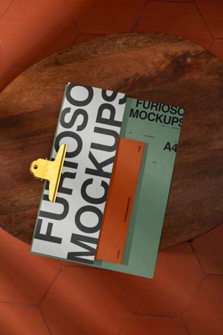 Layered print collateral with bold typography next to green folder on woven surface