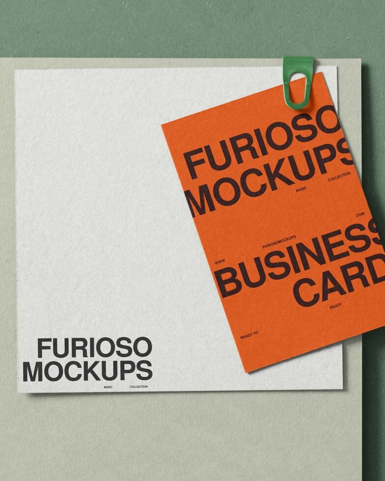 Overhead shot of business card mockup in orange with green paperclip on cream background