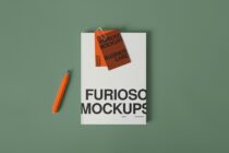 Open magazine mockup with business card floating above, orange pen nearby