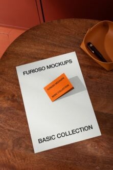 White mockup sheet on wooden table with orange business card sample next to ceramic bowl