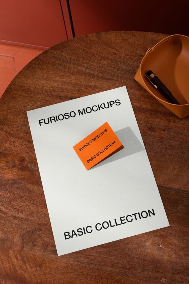 White mockup sheet on wooden table with orange business card sample next to ceramic bowl