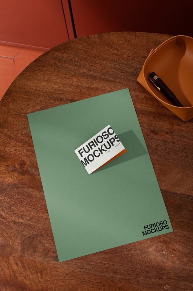 Sage green card mockup on wooden desk with white label showing text on surface
