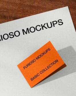 Orange business card mockup casting shadow on white paper with wooden desk surface