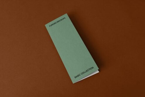 Tall sage green folded brochure with small text on cream base against brown backdrop