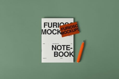 White notebook with orange sticker overlay next to orange marker on sage green background