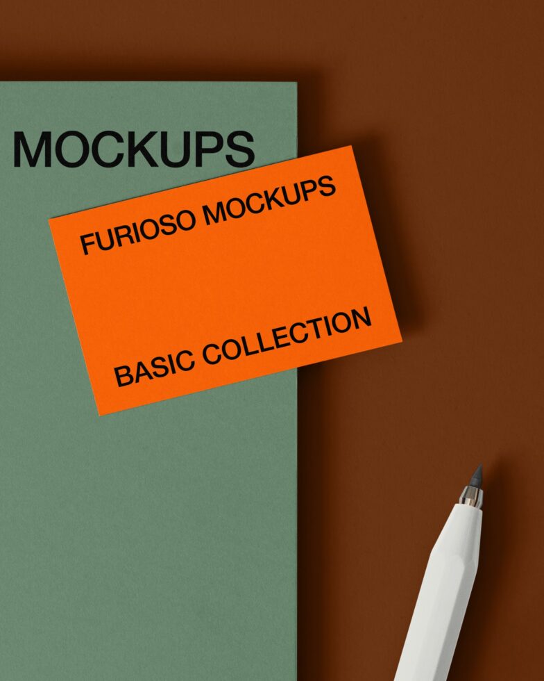 Sage green card with orange card overlay, white pen visible on brown background