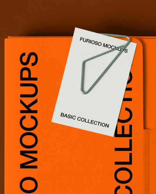 Orange folder with black text next to white card with green clip on brown background