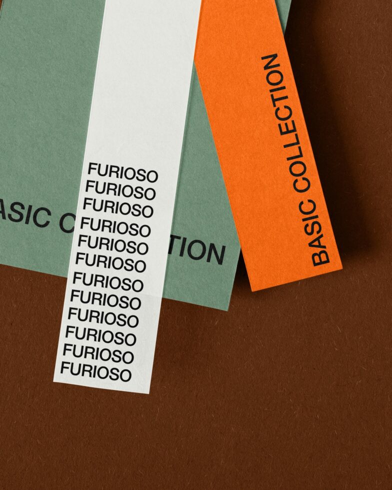 Flat lay of overlapping paper strips in green, white, orange showing repeated text layouts for branding