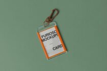 Orange ID card holder with brown carabiner clip on sage green background