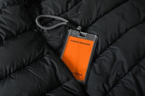Orange card in clear lanyard holder on quilted black jacket with rope strap