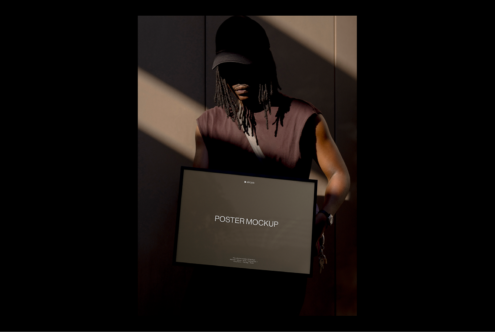 Dark-themed poster mockup held by person in cap, sunlight creates artistic shadows, ideal for designers seeking bold, modern visual assets.