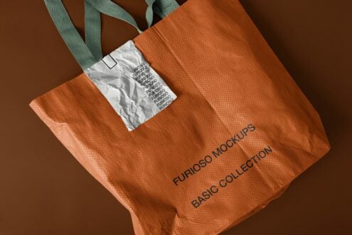Orange textured tote with white wrinkled label, green handles at angled perspective
