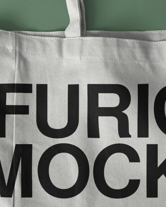 Natural canvas tote bag with thick handles against sage green background showing text