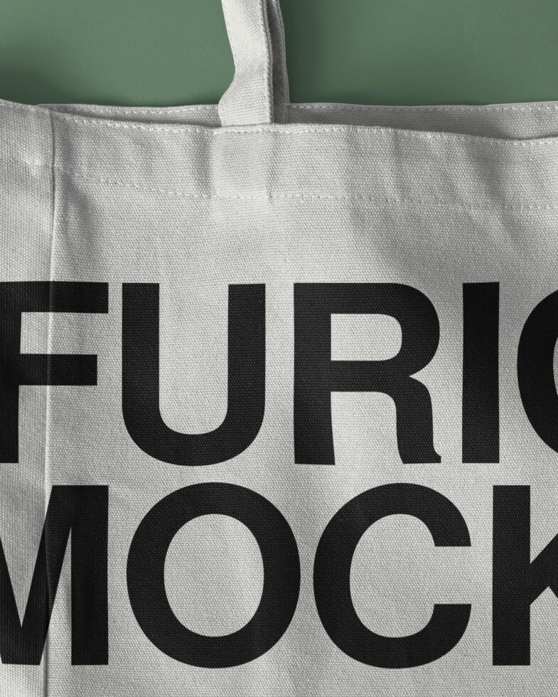 Natural canvas tote bag with thick handles against sage green background showing text