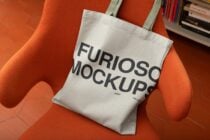 White canvas tote bag with bold black text sitting on bright orange chair