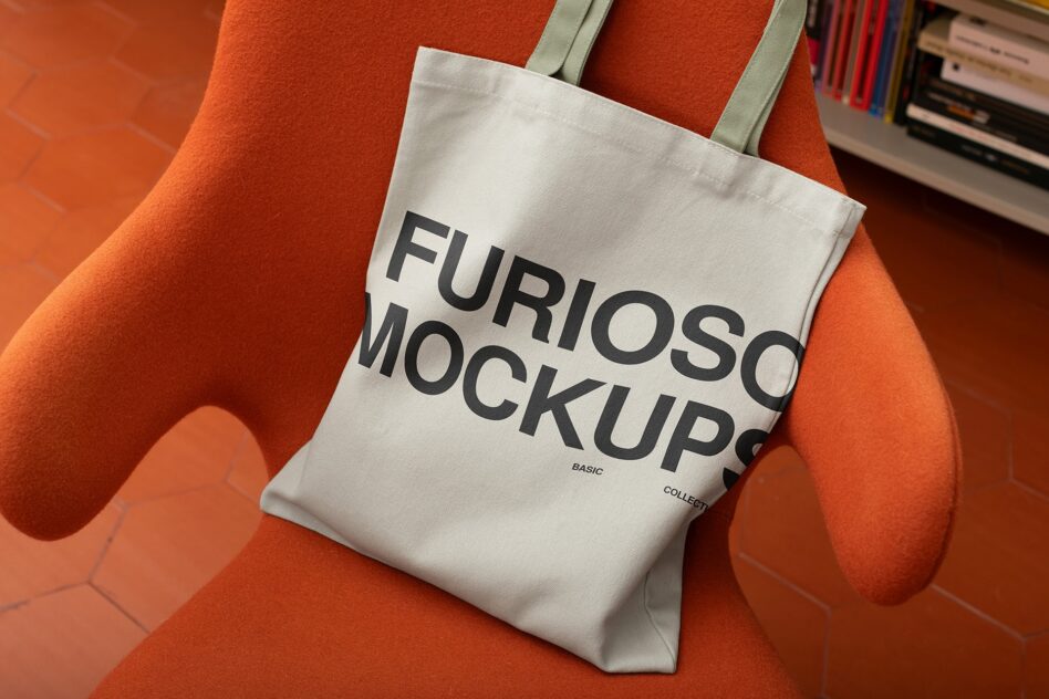 White canvas tote bag with bold black text sitting on bright orange chair