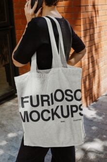 Person carrying natural canvas tote bag on brick wall street