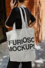 Person carrying natural canvas tote bag on brick wall street