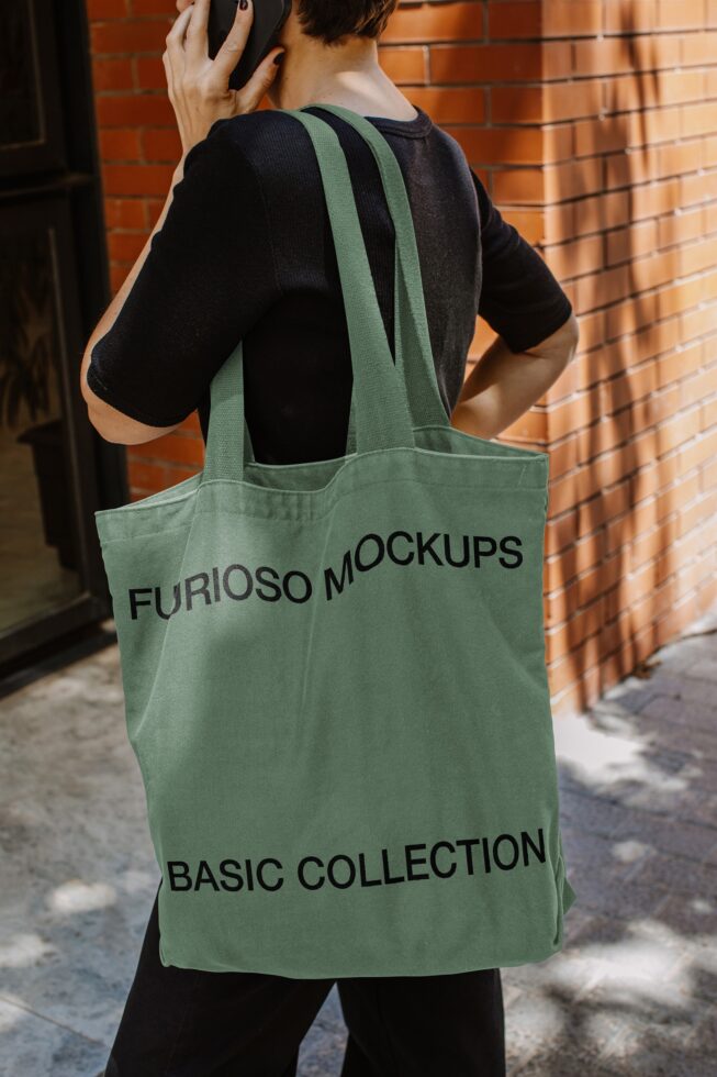 Person wearing green tote bag from behind on brick wall street