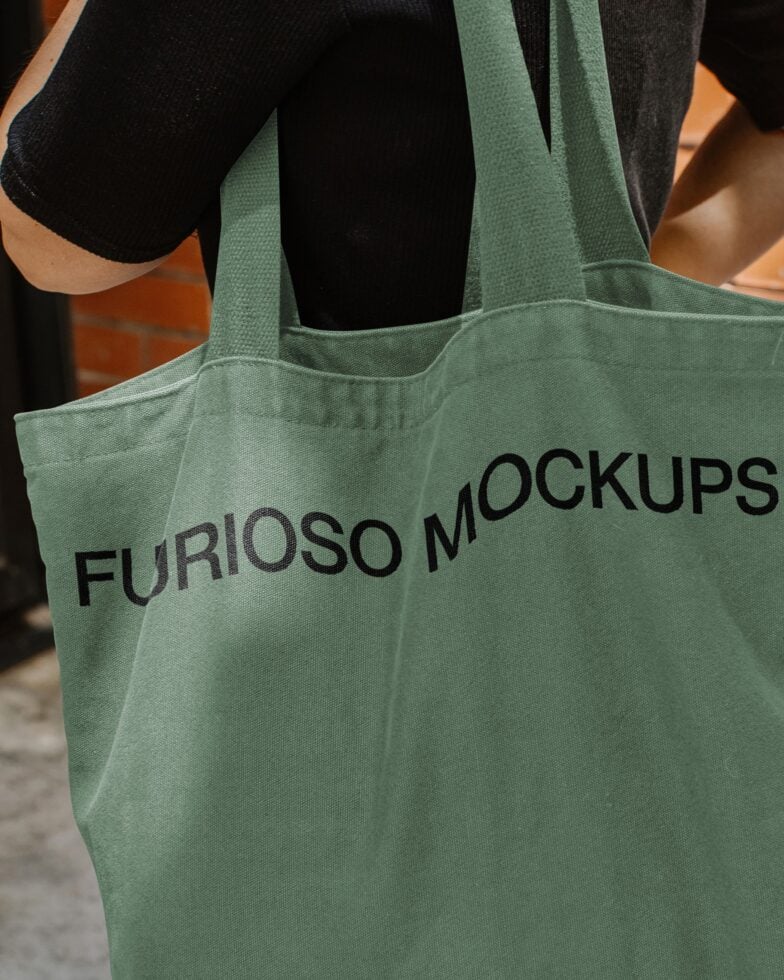 Green canvas tote bag closeup with black text on fabric