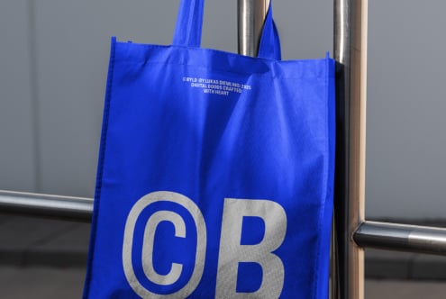 Royal blue tote showing large silver CB initials on metal rail