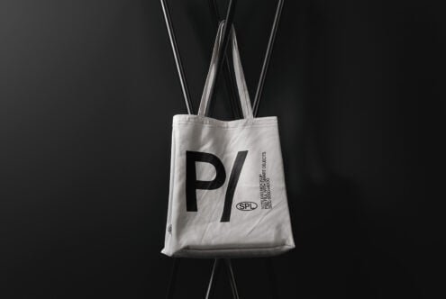 White tote bag mockup showing large P logo with text detail on dark backdrop