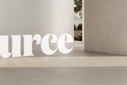 Oversized white serif characters in bright gallery with window overlooking landscape