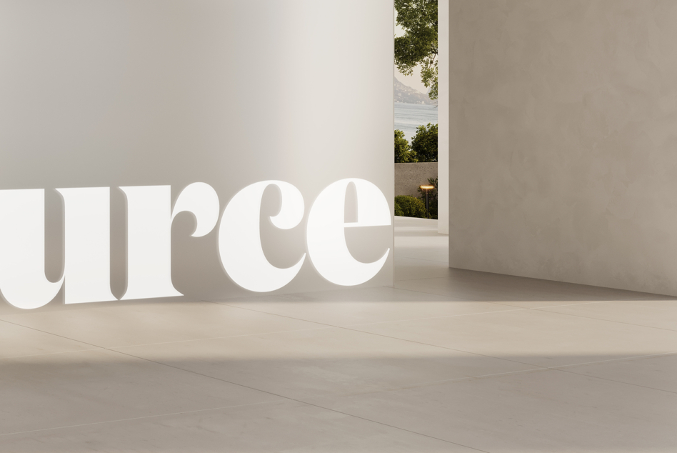 Oversized white serif characters in bright gallery with window overlooking landscape