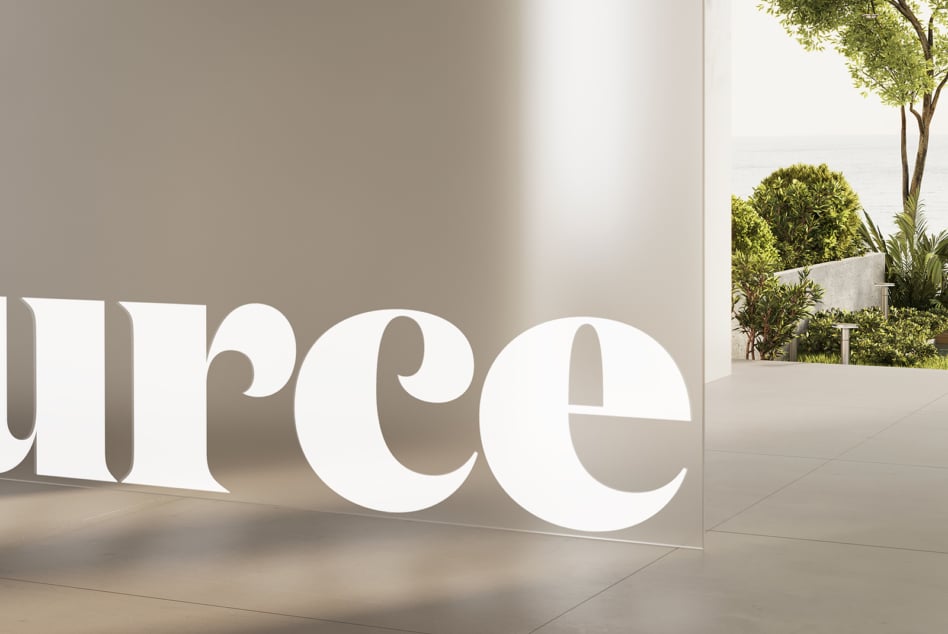 Large white 3D letters casting shadows on outdoor plaza with greenery