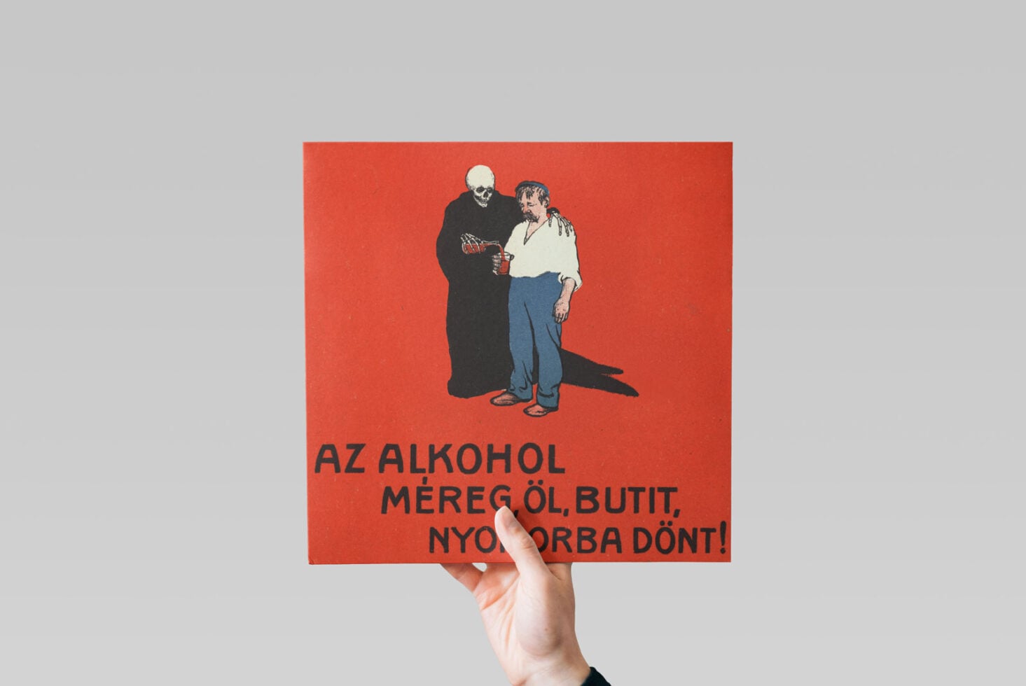 Vintage red poster with skull character, Hungarian text, held up against library shelves