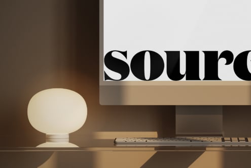 Close up of monitor screen showing large black serif letters against white with soft desk lamp glow