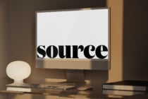 Desktop monitor displaying bold black serif typography on white background with warm studio lighting