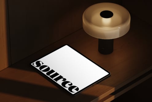 Tablet with brass lamp above on dark wood floor showing Source